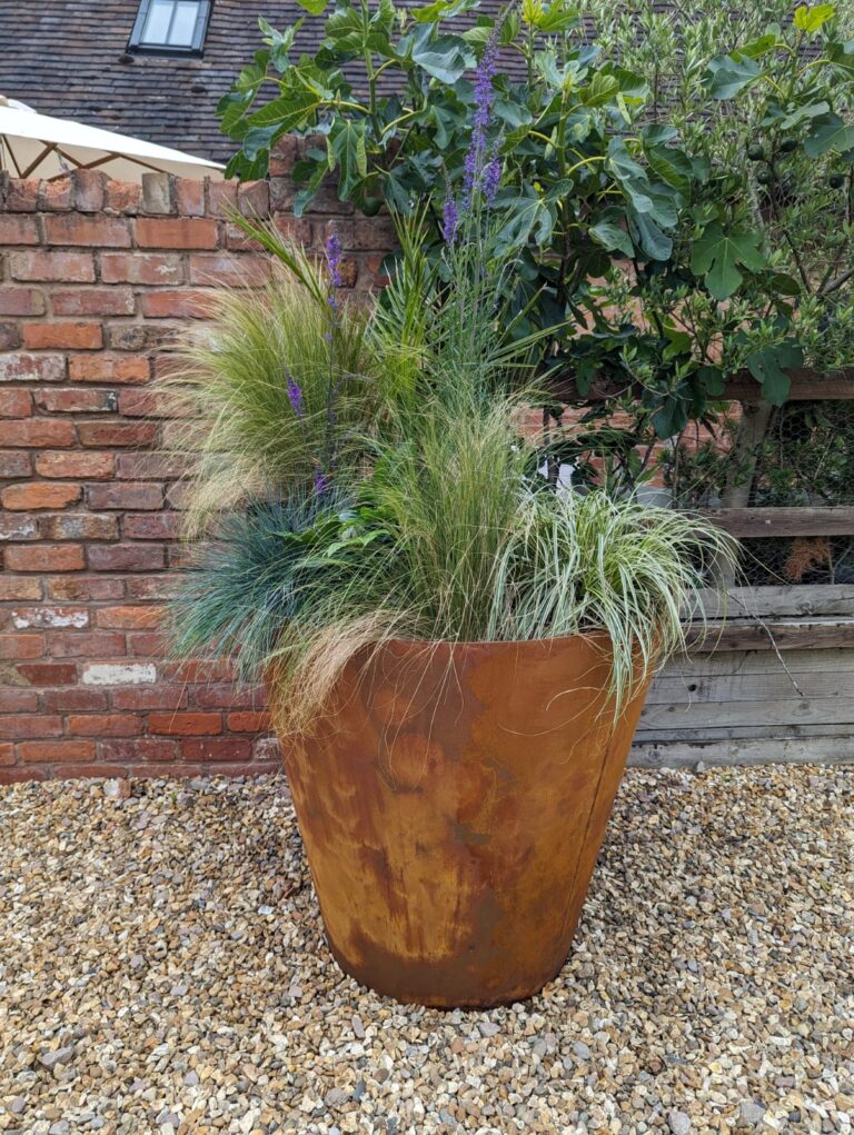 Very large Corten weathered steel planter custom made by Winthill Engineering for a private customer shown here planted with ornamental grasses and shrubs.