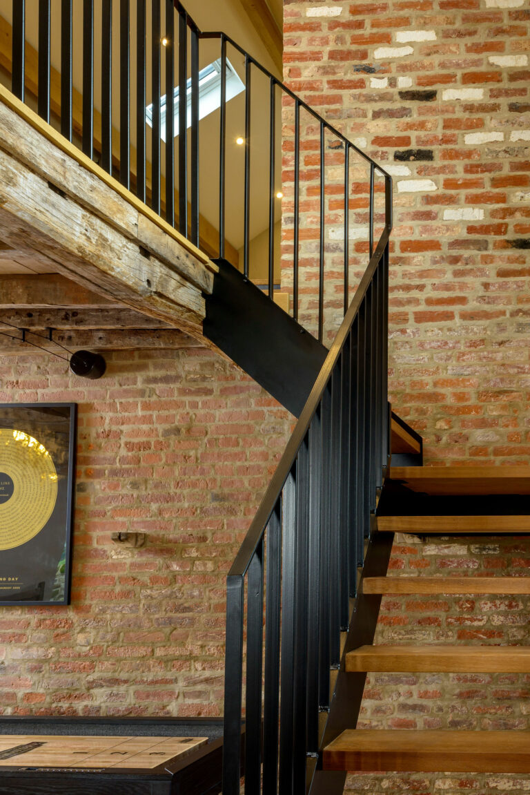 Close up of curved steel balustrade of a bespoke steel and timber staircase by Winthill Engineering for an 18th century barn conversion in Shropshire